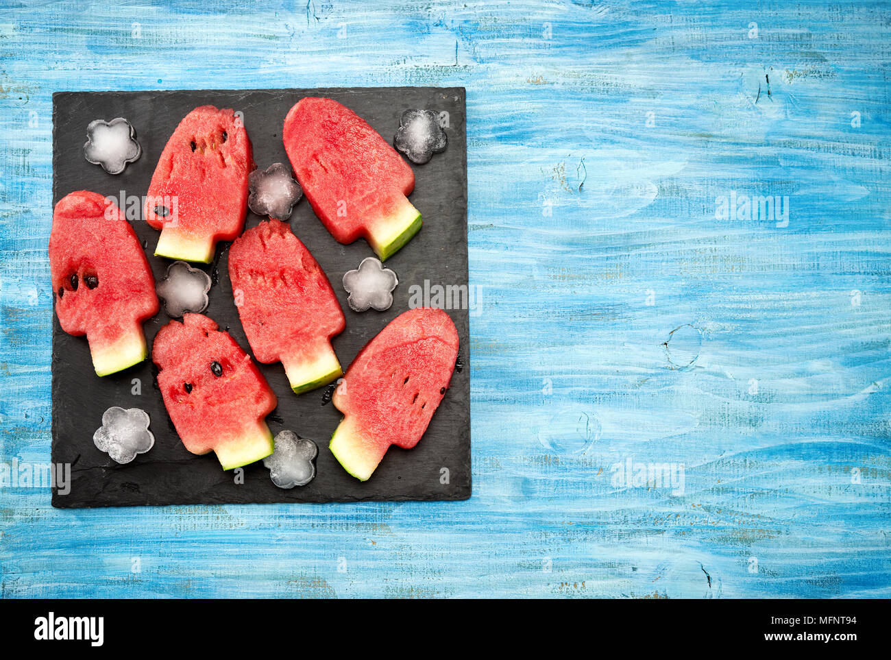 Watermelon peaces cut in ice cream lolly pop shape on bright blue background Stock Photo