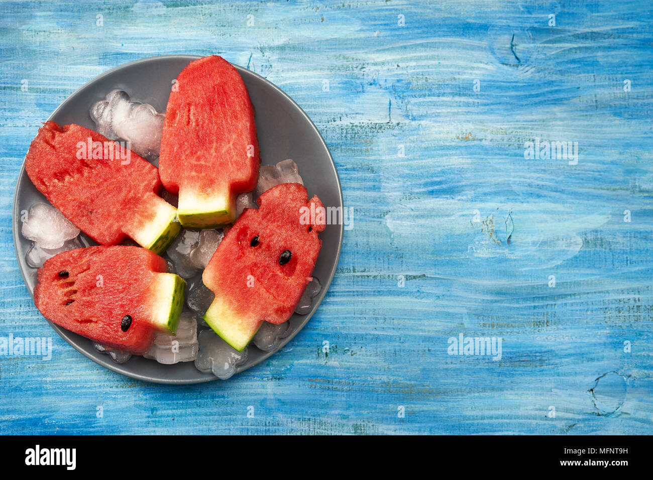 Watermelon peaces cut in ice cream lolly pop shape on bright blue background Stock Photo