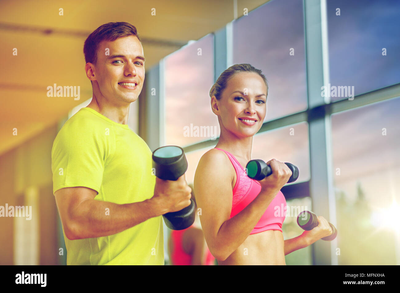 smiling man and woman with dumbbells in gym Stock Photo - Alamy