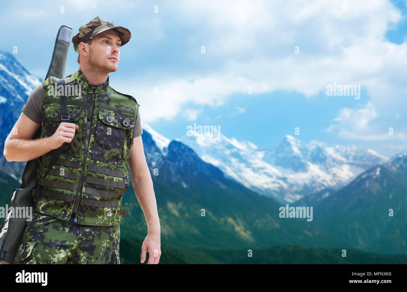 young soldier or hunter with gun over mountains Stock Photo