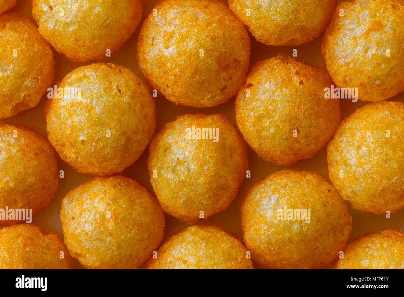 Background of extruded puff cheese balls from above. Stock Photo