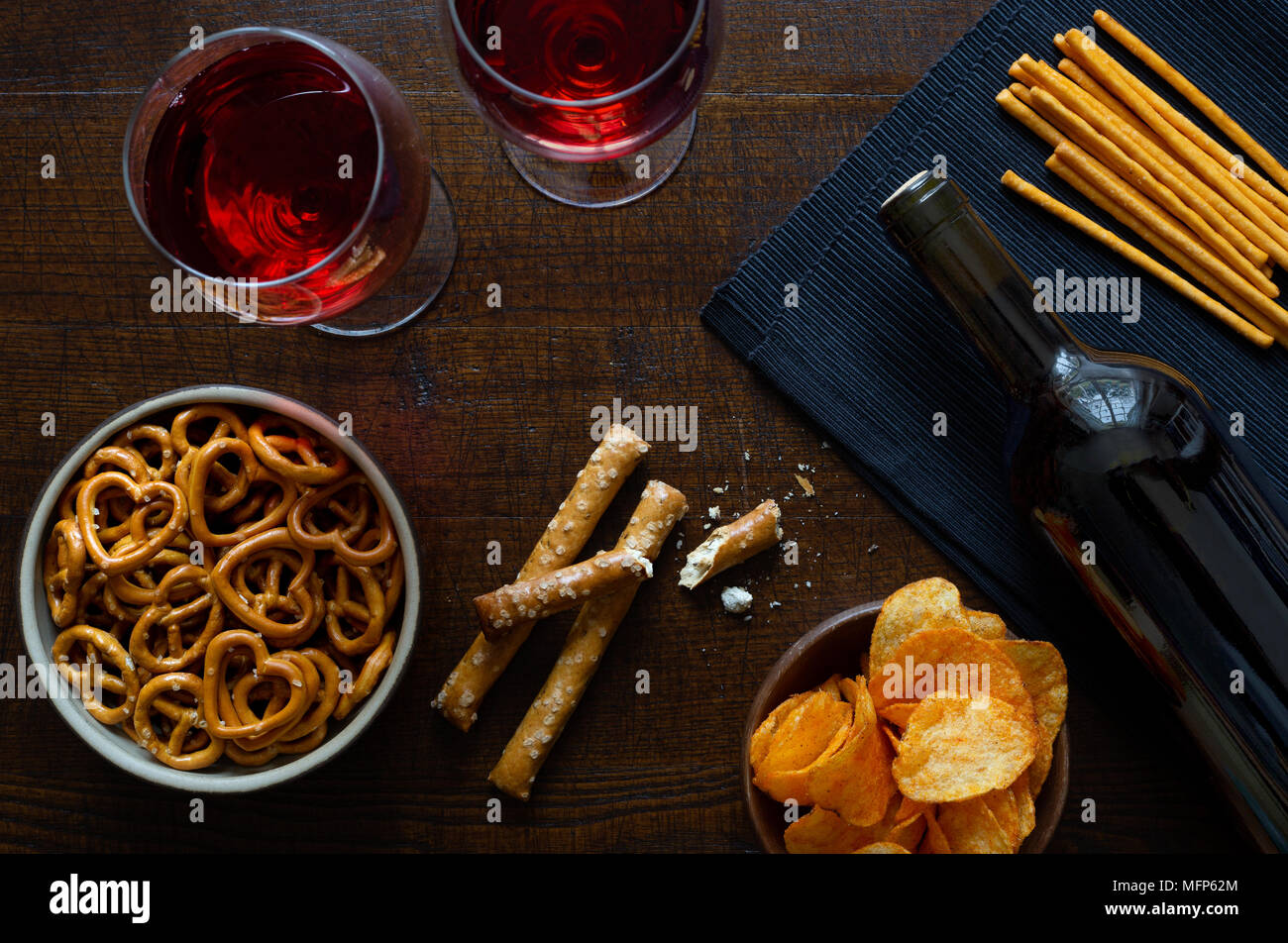 Red wine with savoury party snacks on rustic dark wood background from above. Stock Photo