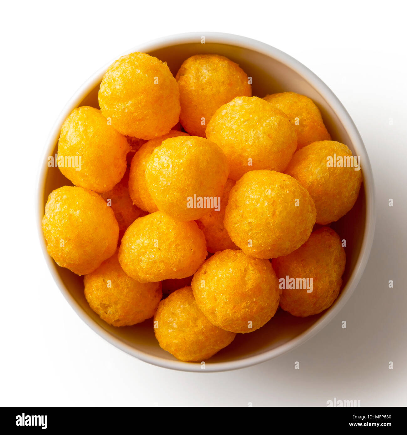 Extruded puffed cheese balls in white ceramic dish isolated on white from above. Stock Photo
