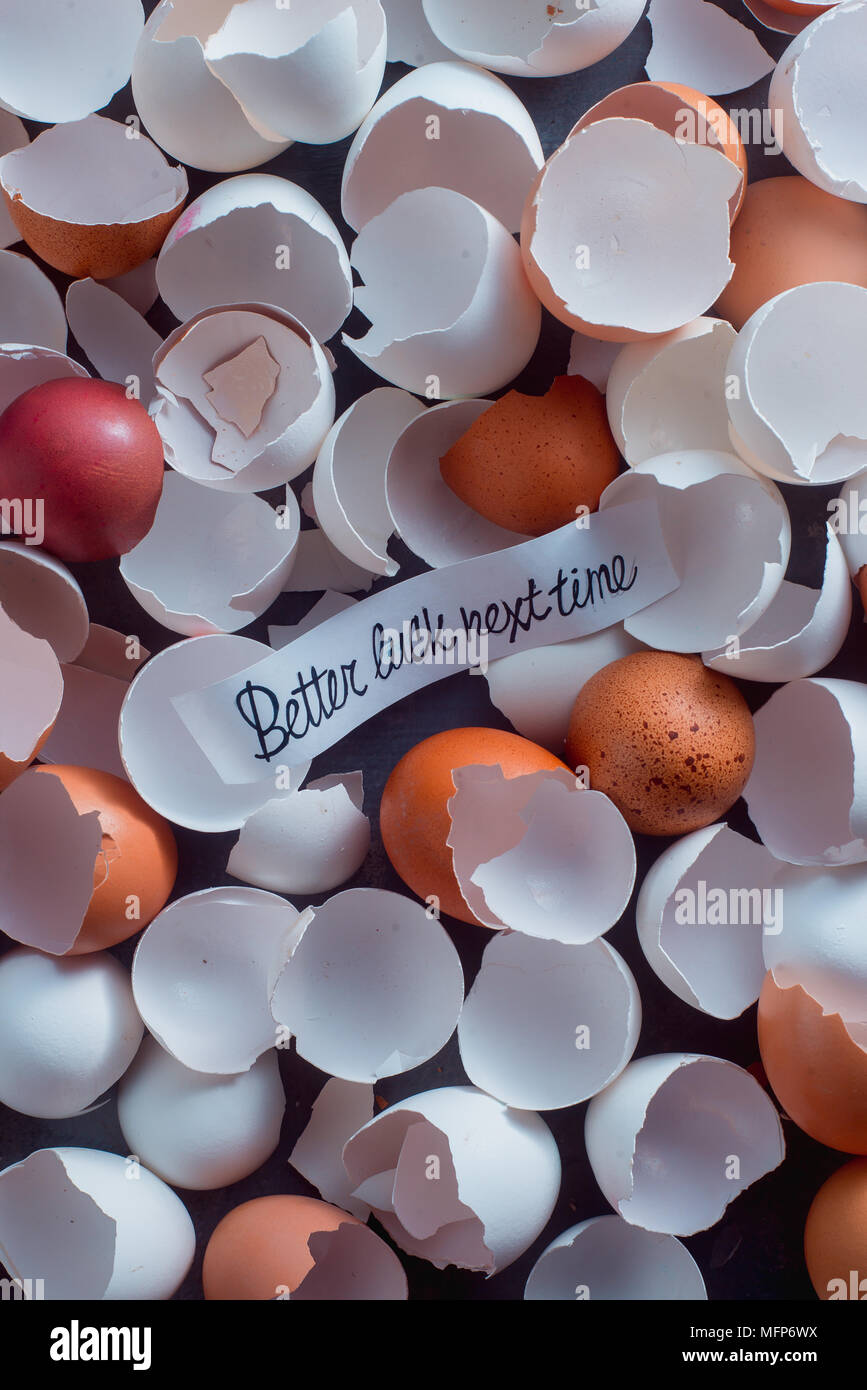 Broken open eggshells of white and brown chicken eggs left from baking with a note Better Luck Next Time. Winning a lottery or finding a prize concept Stock Photo