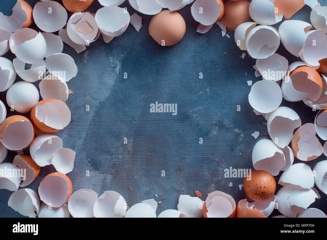 Empty, cracked and broken open eggshells of white and brown chicken eggs ready to go into organic waste. Baking leftover on a concrete background with Stock Photo