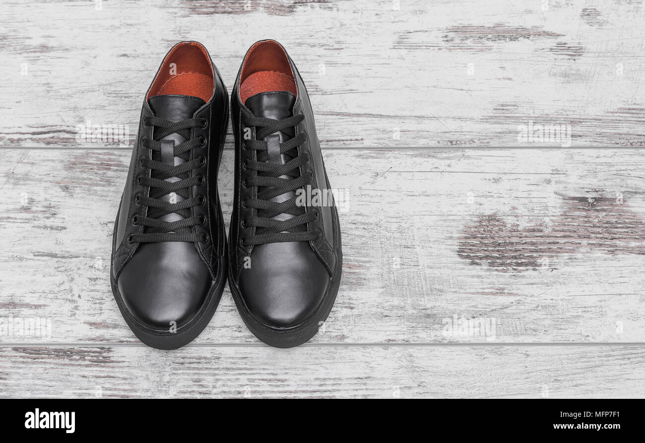 Black leather sneakers on a light laminate. Stock Photo