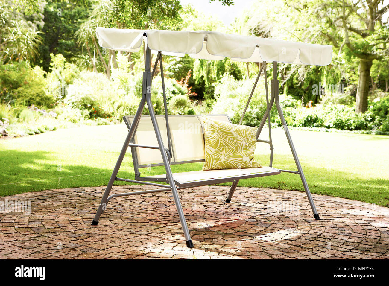 Swing seat with shade on paved patio in garden Stock Photo
