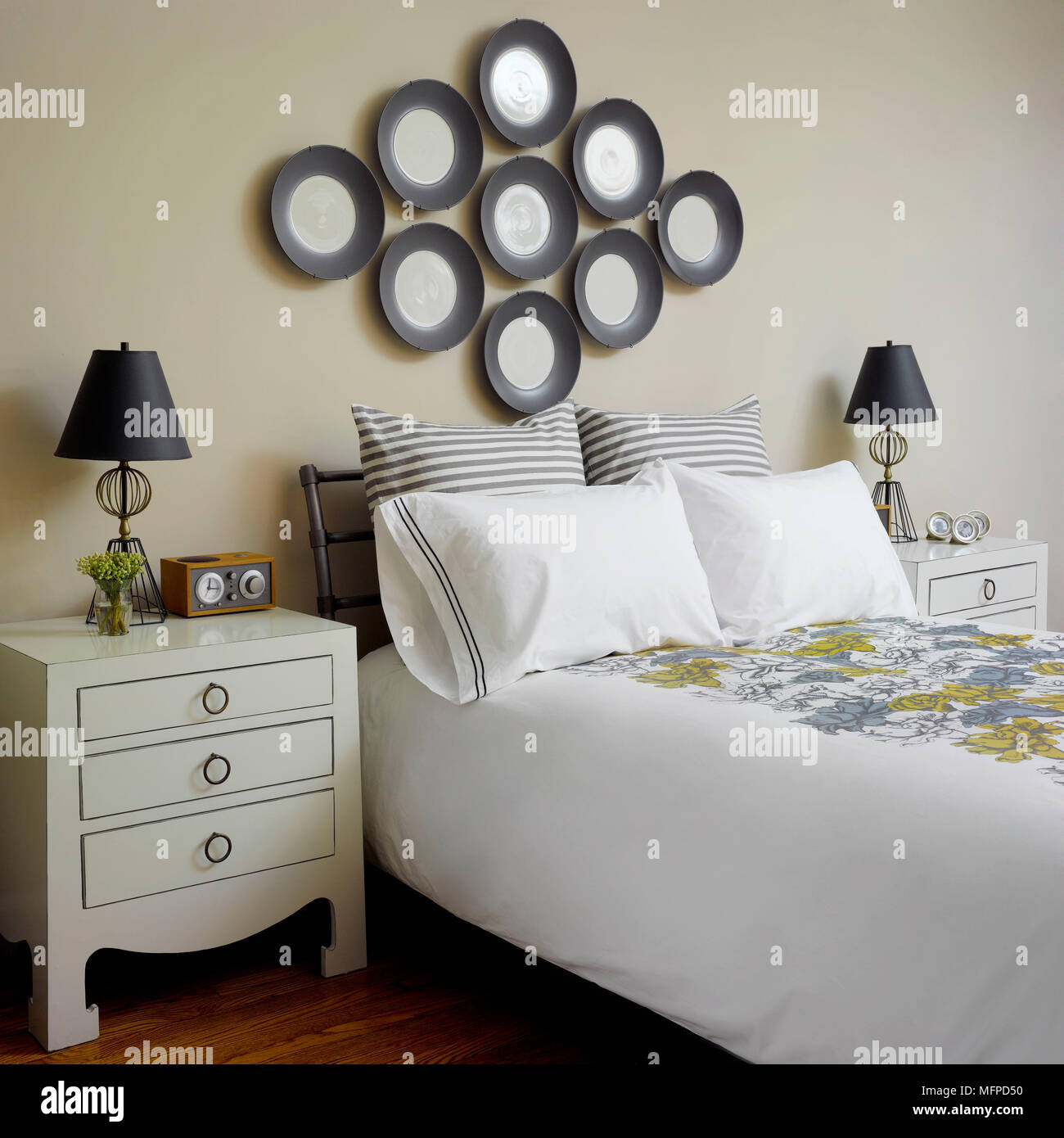 Lamp on chest of drawers beside double bed in traditional style bedroom