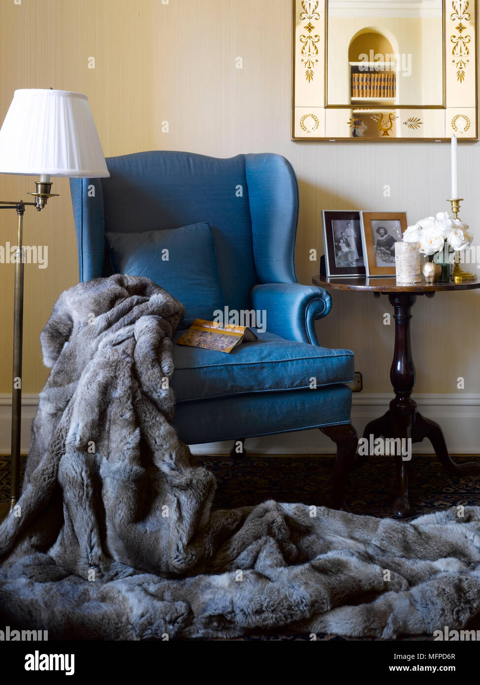 Fur throw over arm of traditional armchair next to three legged table, New York, USA Stock Photo