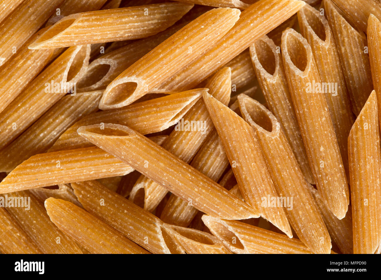 Close up of uncooked whole wheat penne pasta. Food background image. Stock Photo