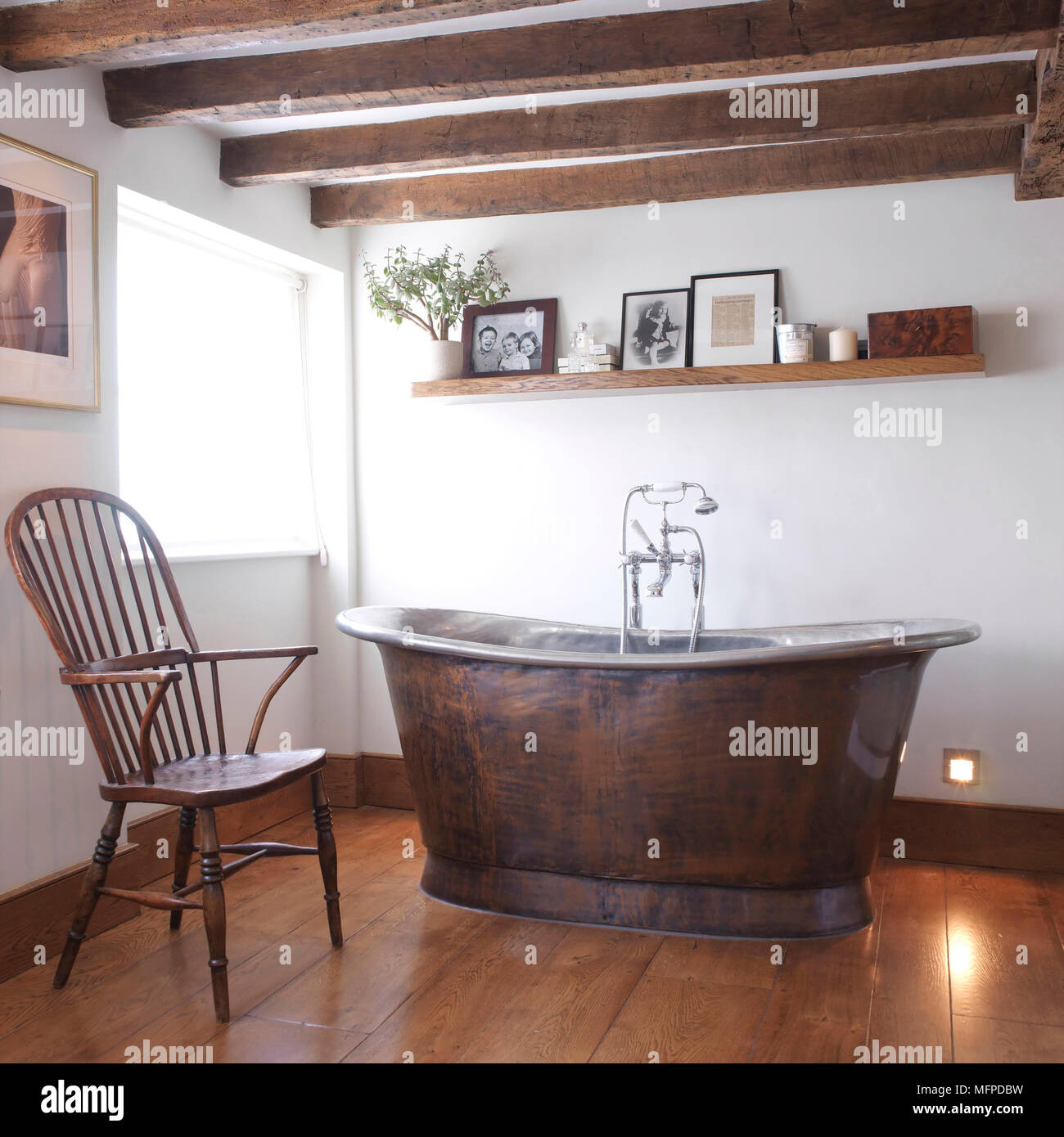 Freestanding old fashioned bathtub in centre of country style bathroom