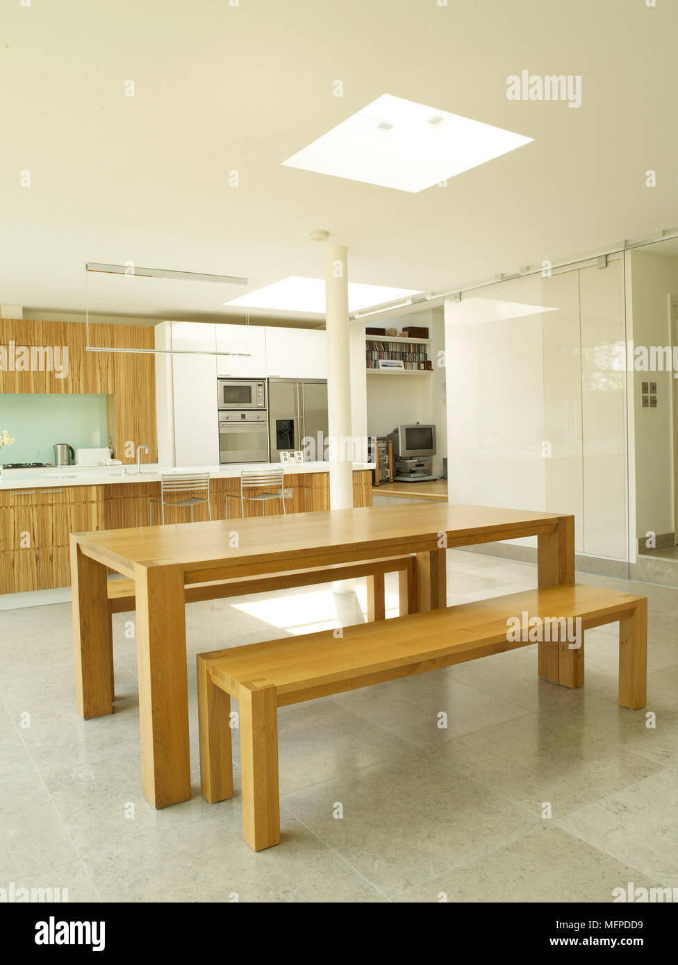 Simple wooden table and bench seats in the centre of contemporary kitchen Stock Photo