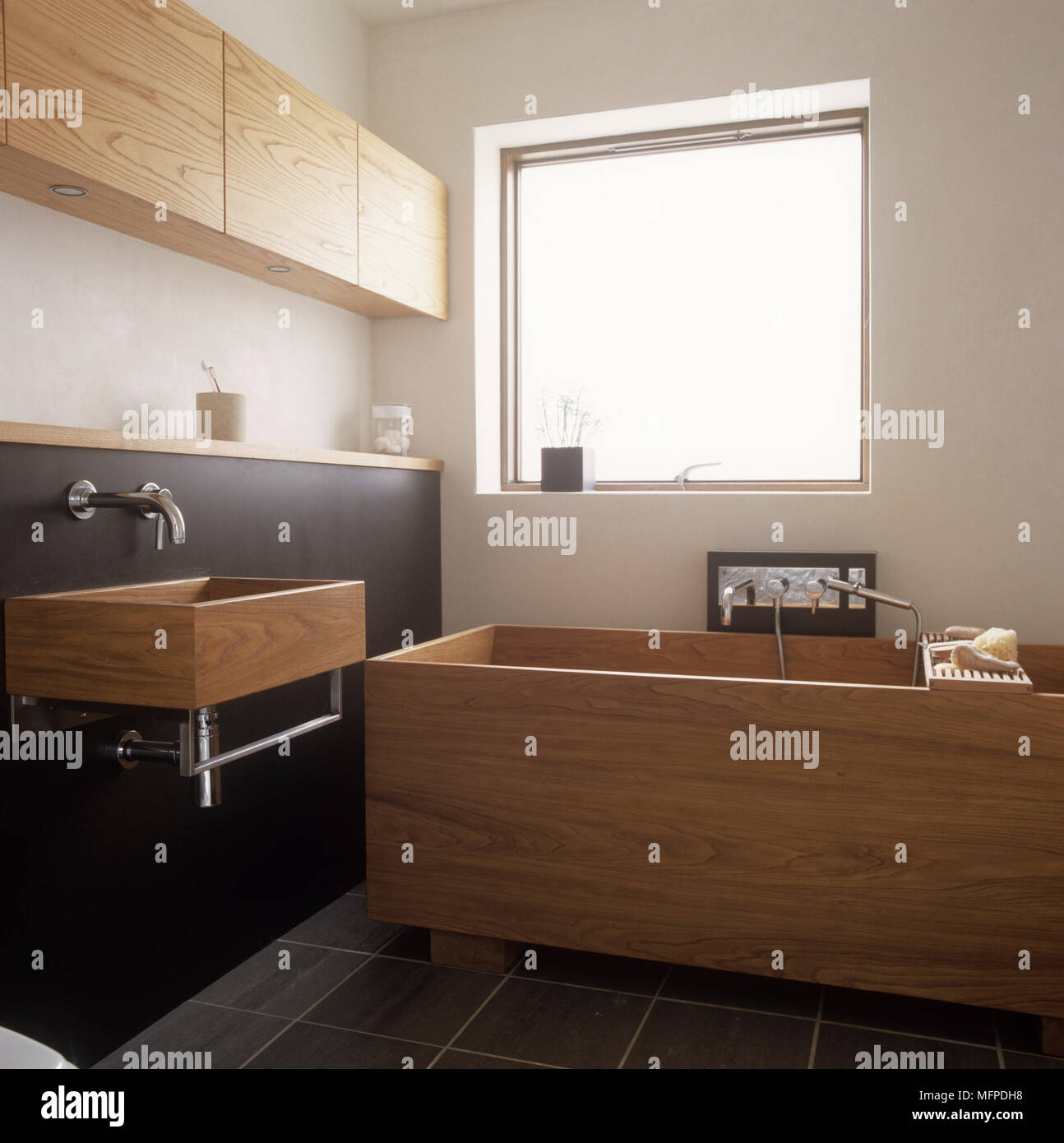 Wooden washbasin and bathtub below window Stock Photo - Alamy