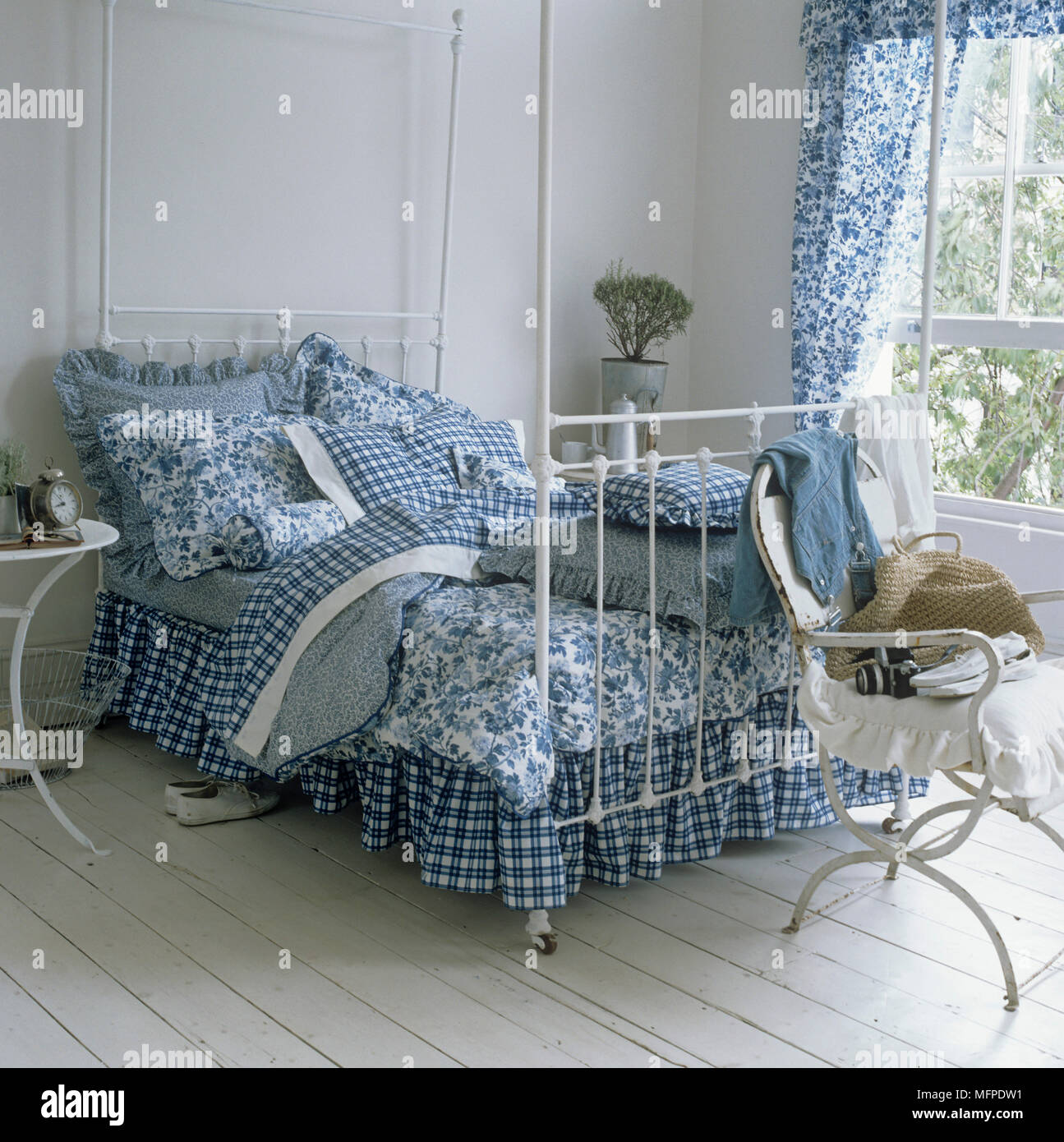 White Painted Wrought Iron Bed With Blue And White Covers Stock