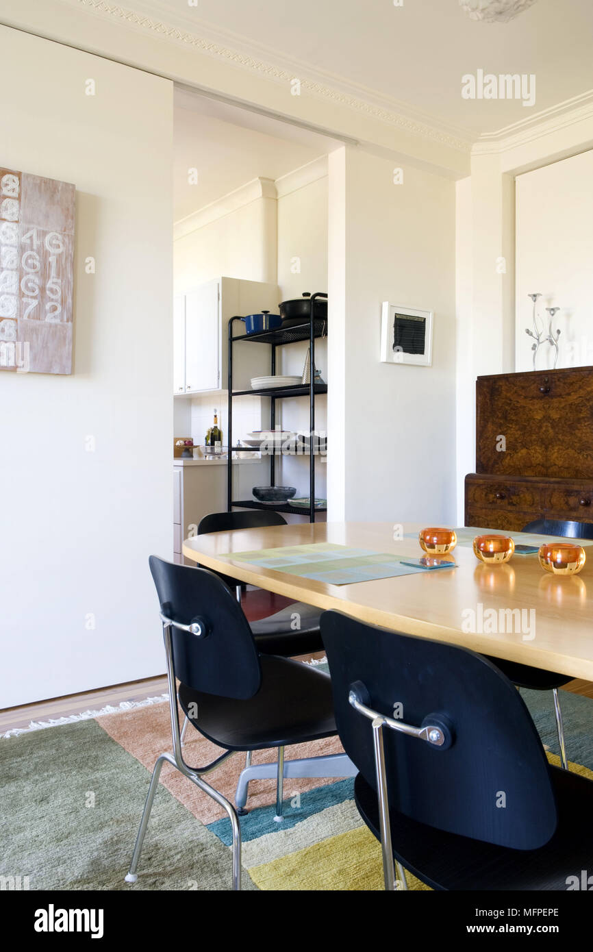 Black Chairs At Wooden Table In Modern Dining Room With Sliding Doors Giving View To Kitchen Black Chairs At Wooden Table In Modern Dining Room With Sliding Doors Giving View To Kitchen