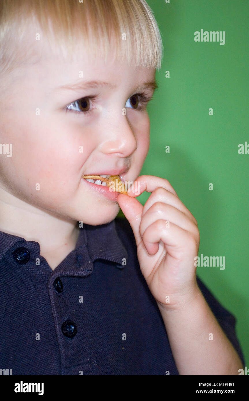 Close-up of a boy looking away whilst eating crisps   Ref: CRUSC 10032 047  Compulsory Credit: Stuart Cox/ Photoshot Stock Photo