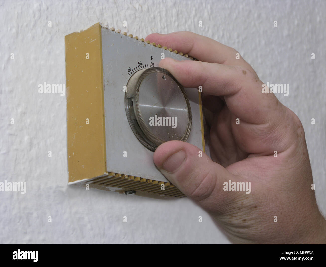 Energy efficiency man lowering the thermostat on the central heating