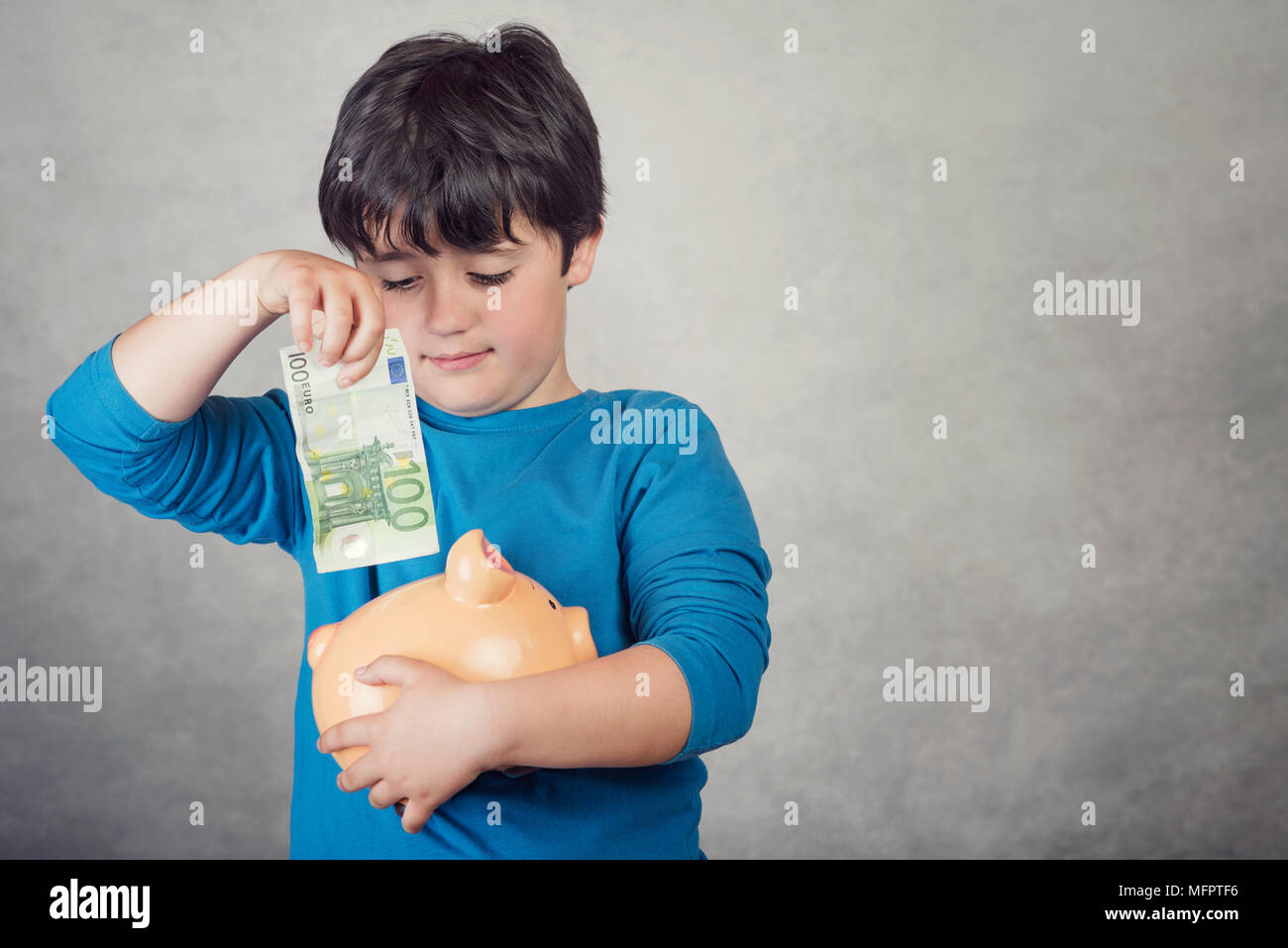 child saving money in a piggy bank on gray background Stock Photo - Alamy