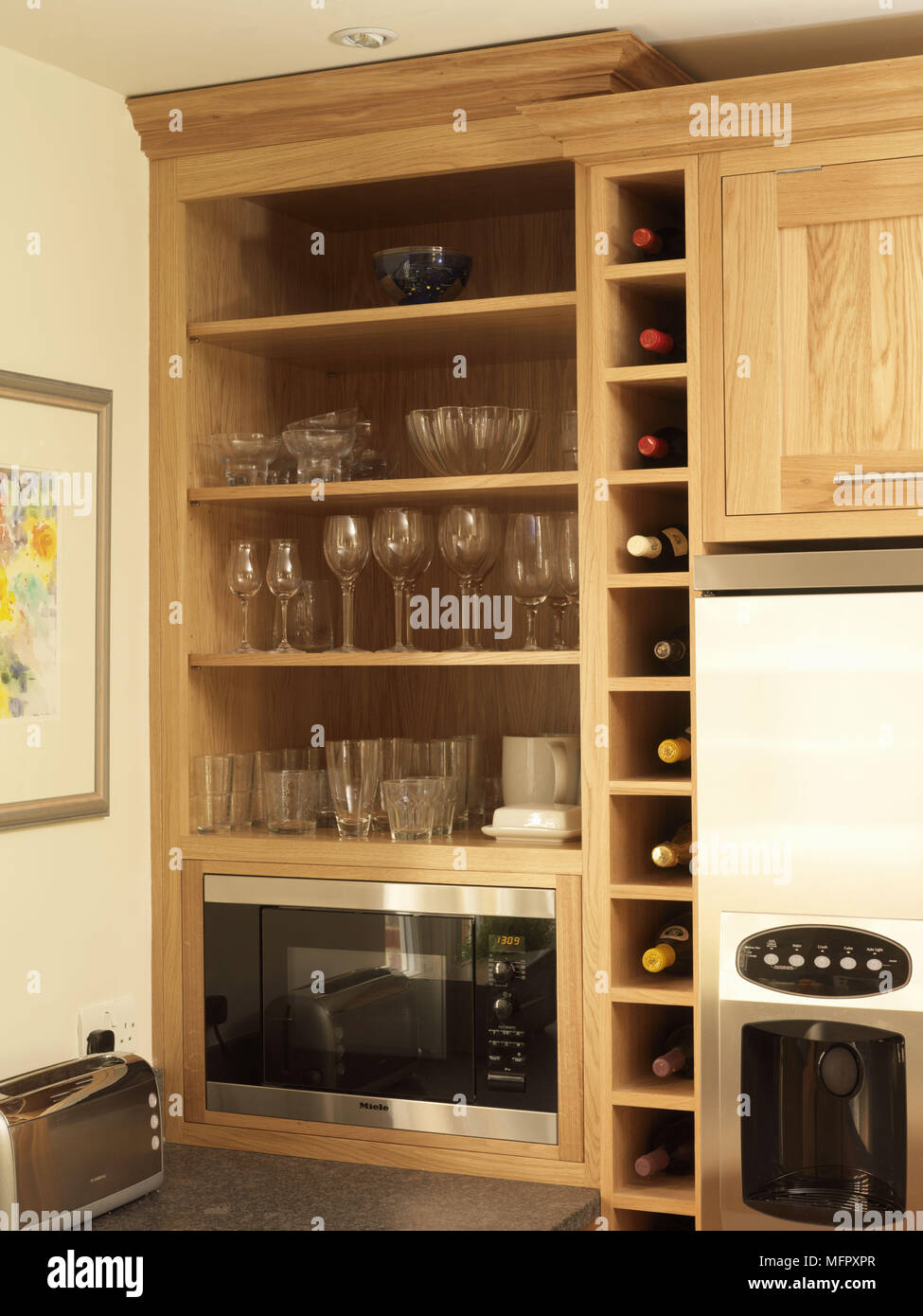 Glassware displayed in shelving unit in kitchen with wood fitted units