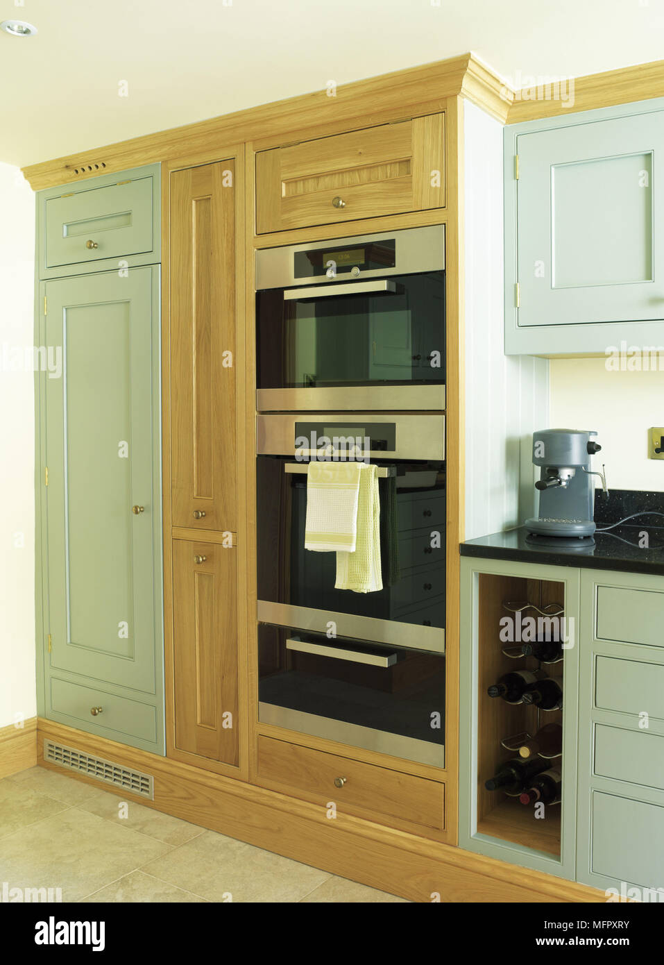 Integral ovens in country style kitchen with green fitted units Stock