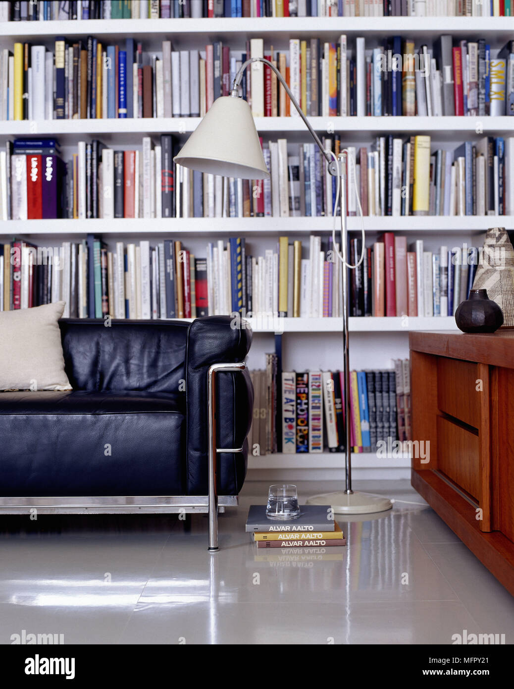 Book-lined shelves in modern sitting room with metal framed sofa floor lamp  and credenza Stock Photo - Alamy