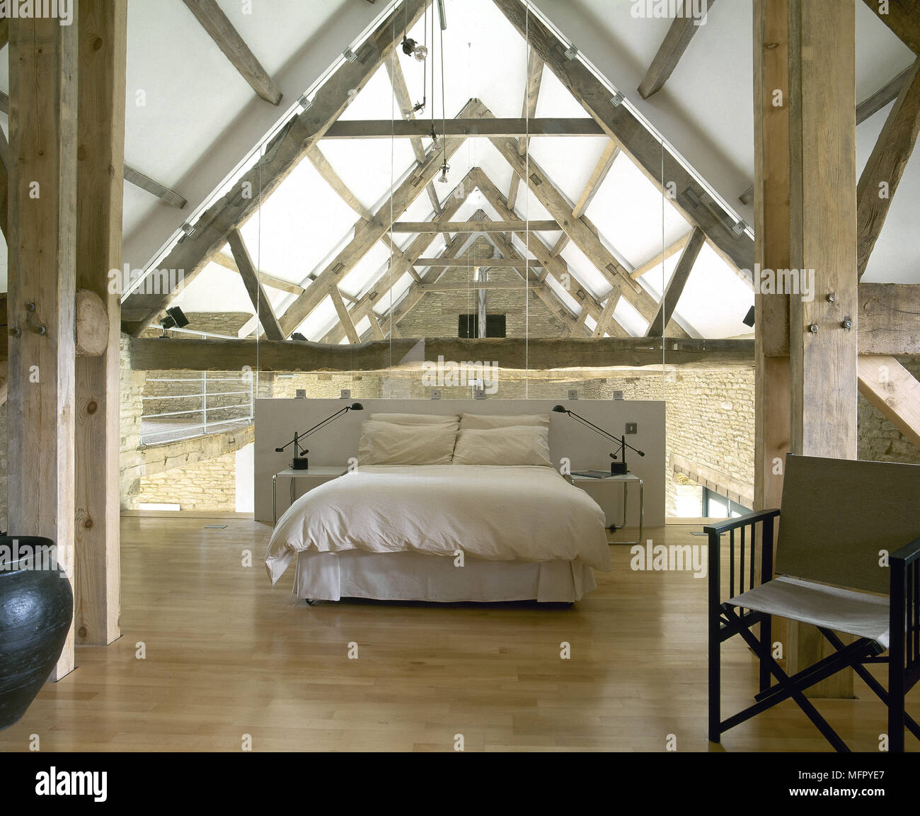 Loft bedroom in a converted barn with a wood floor, exposed roof