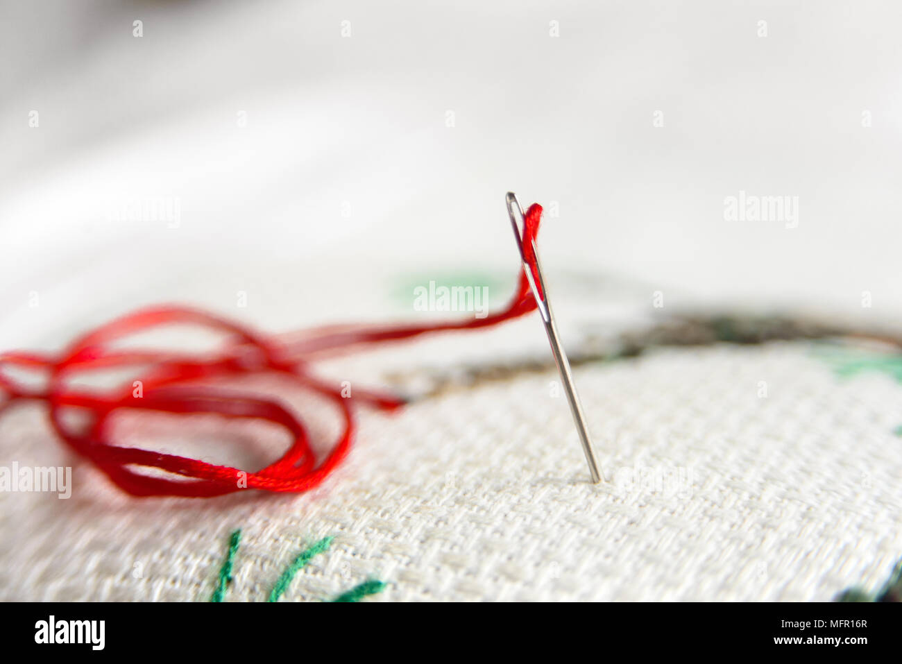 Cross-stitch embroidery and needle with red thread. Embroidery macro close  up. View from above. Free copy space Stock Photo - Alamy