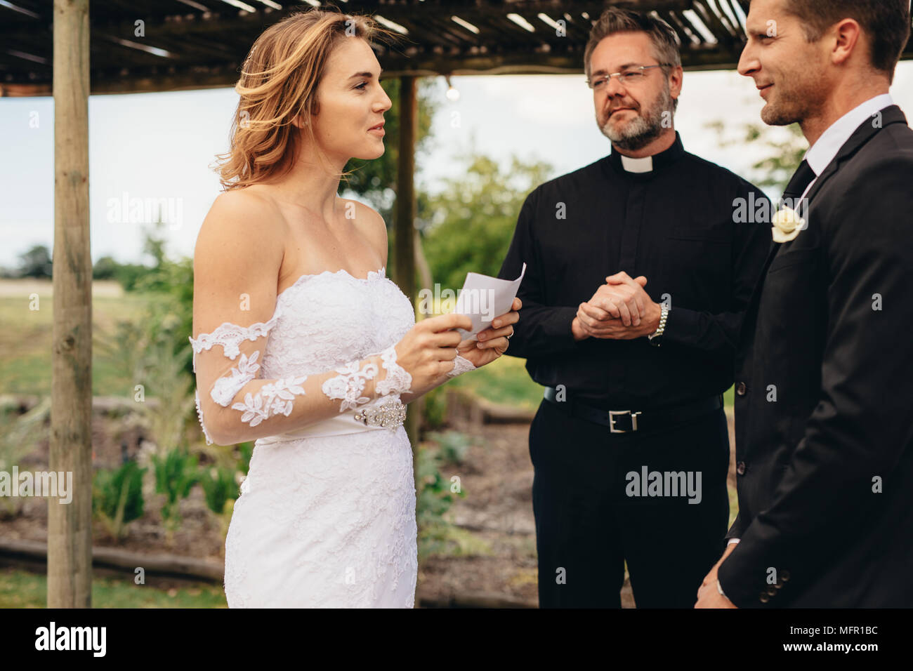 Beautiful young bride reading wedding vows from a paper. wedding ceremony rituals of young couple. Stock Photo