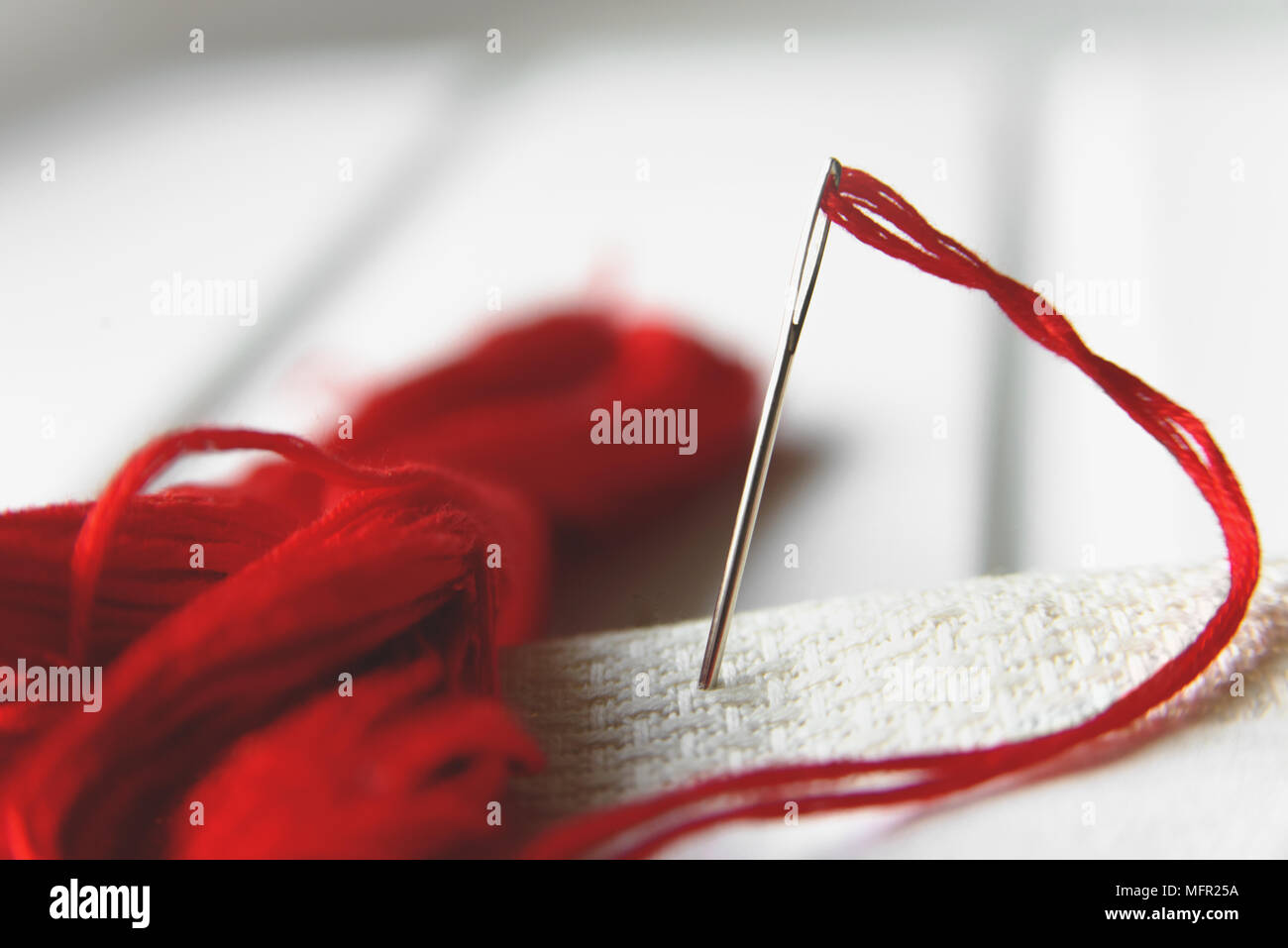 A Needle and red thread over white Stock Photo - Alamy