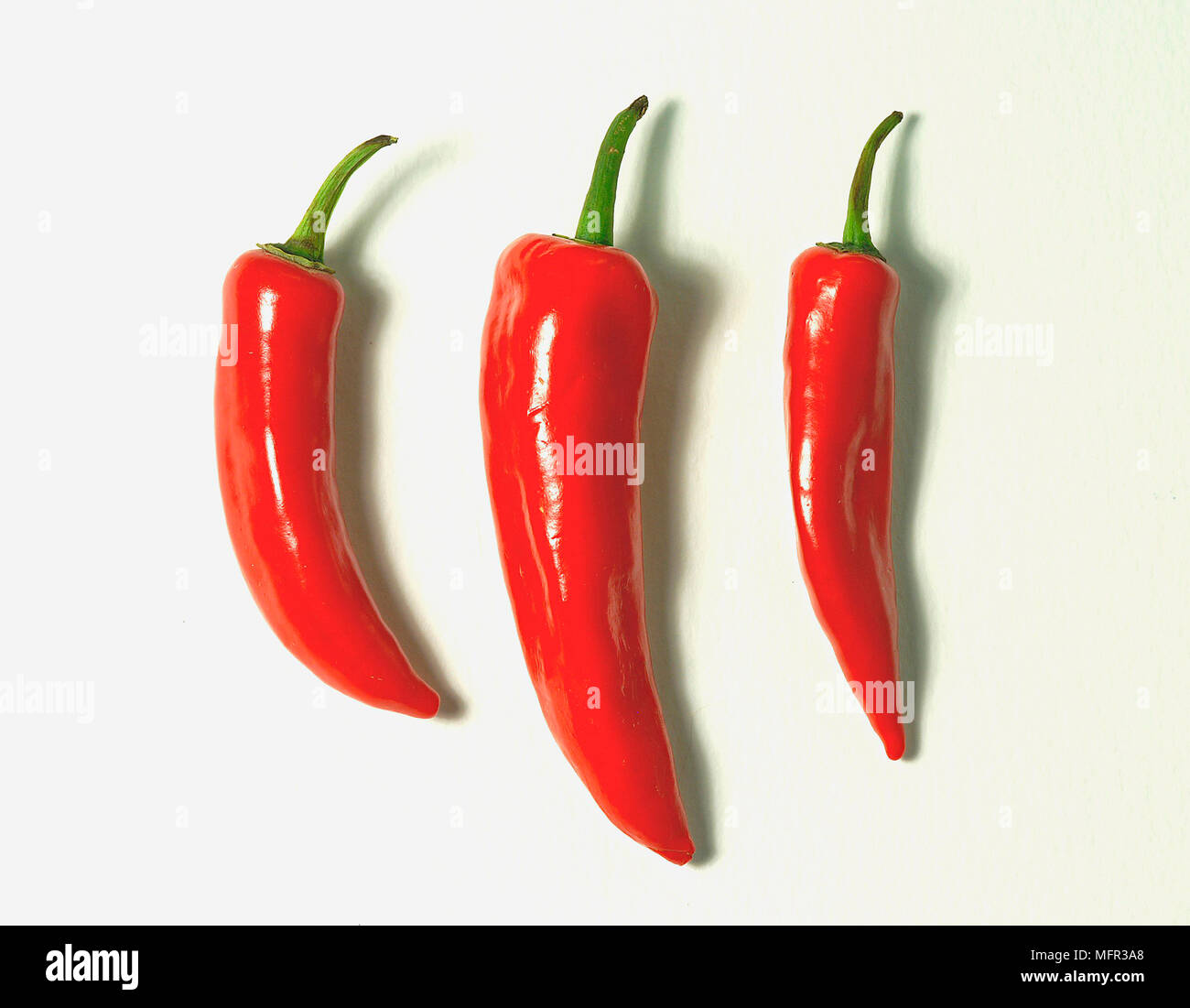 Three red chilli peppers against white background Stock Photo - Alamy