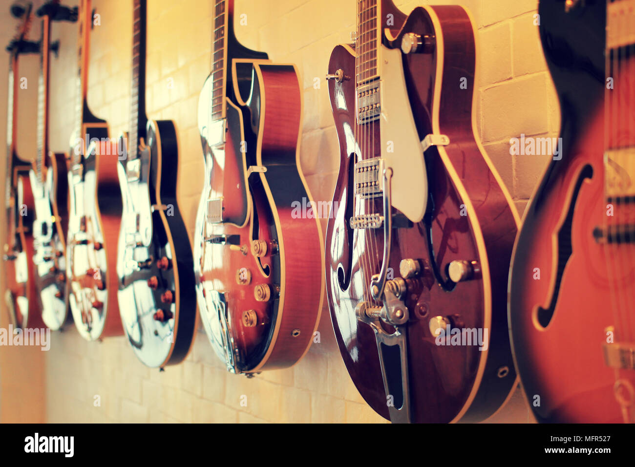 Electric guitars aligned on wall Stock Photo