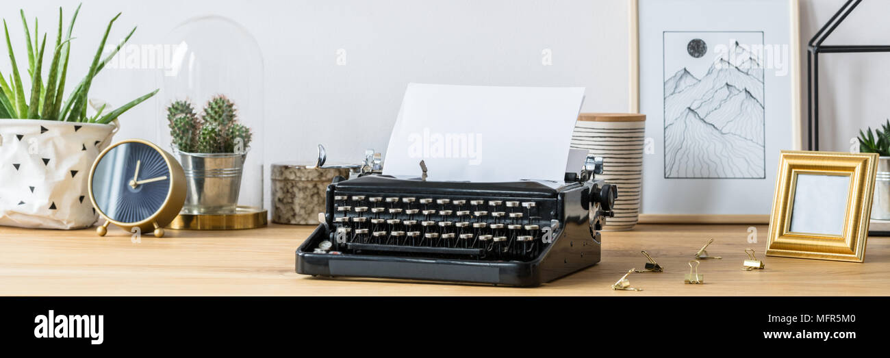 Vintage typewriter standing on a wooden home office desk with fresh