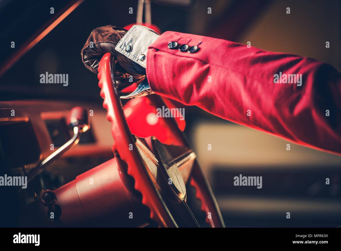 Elegant Classic Car Driver. Retro Styled Men in the Red Suit Driving His American Classic Vehicle. Closeup Photo. Stock Photo