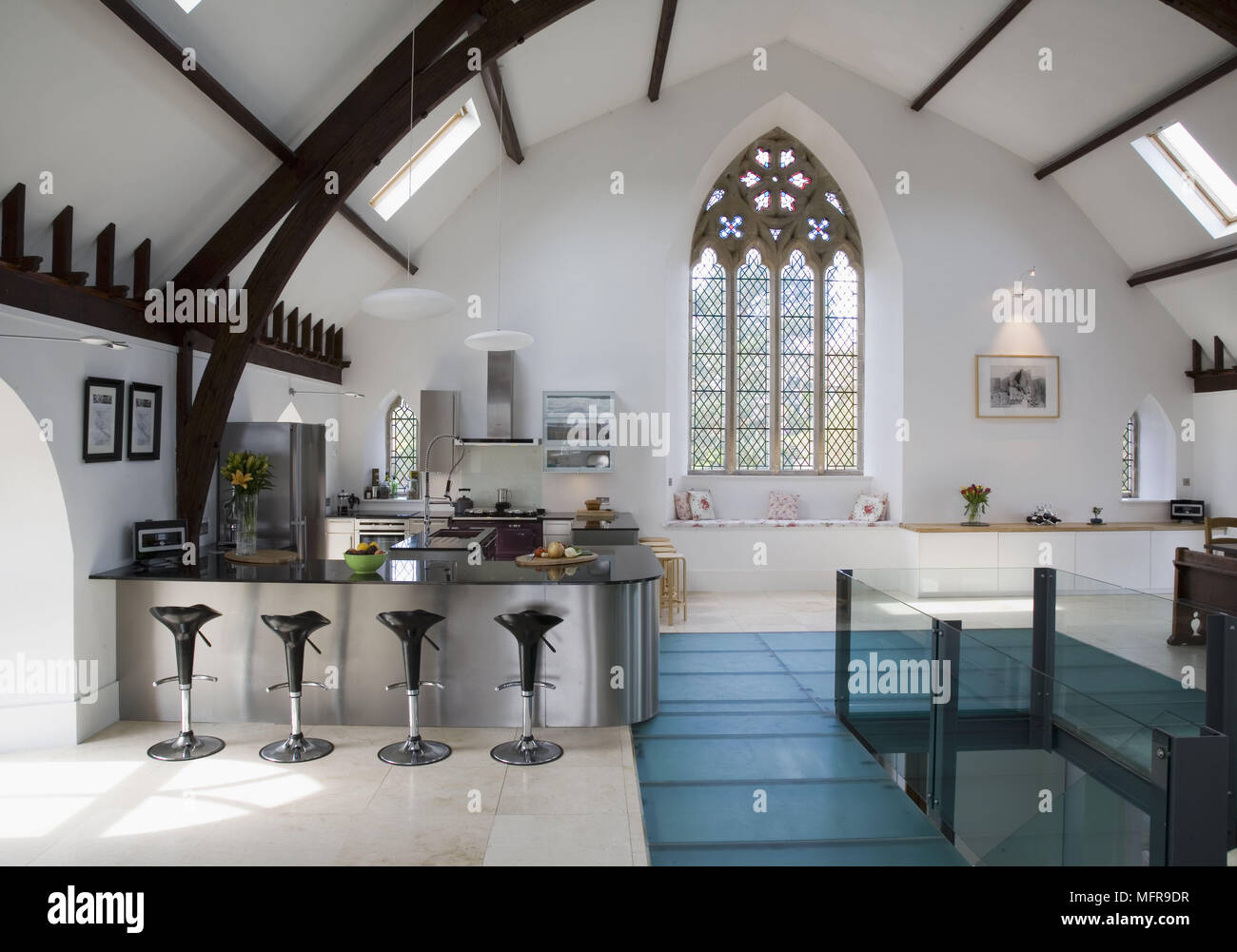 Bar stools at breakfast bar in spacious contemporary kitchen in converted church Stock Photo