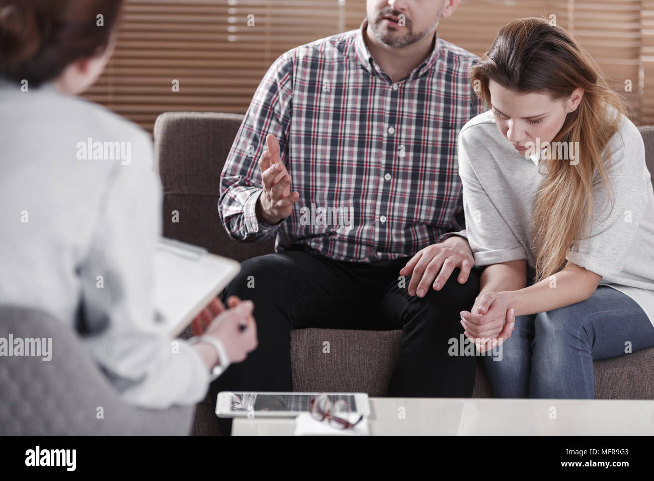Depressed marriage talking to a mediator during therapy for couples Stock Photo