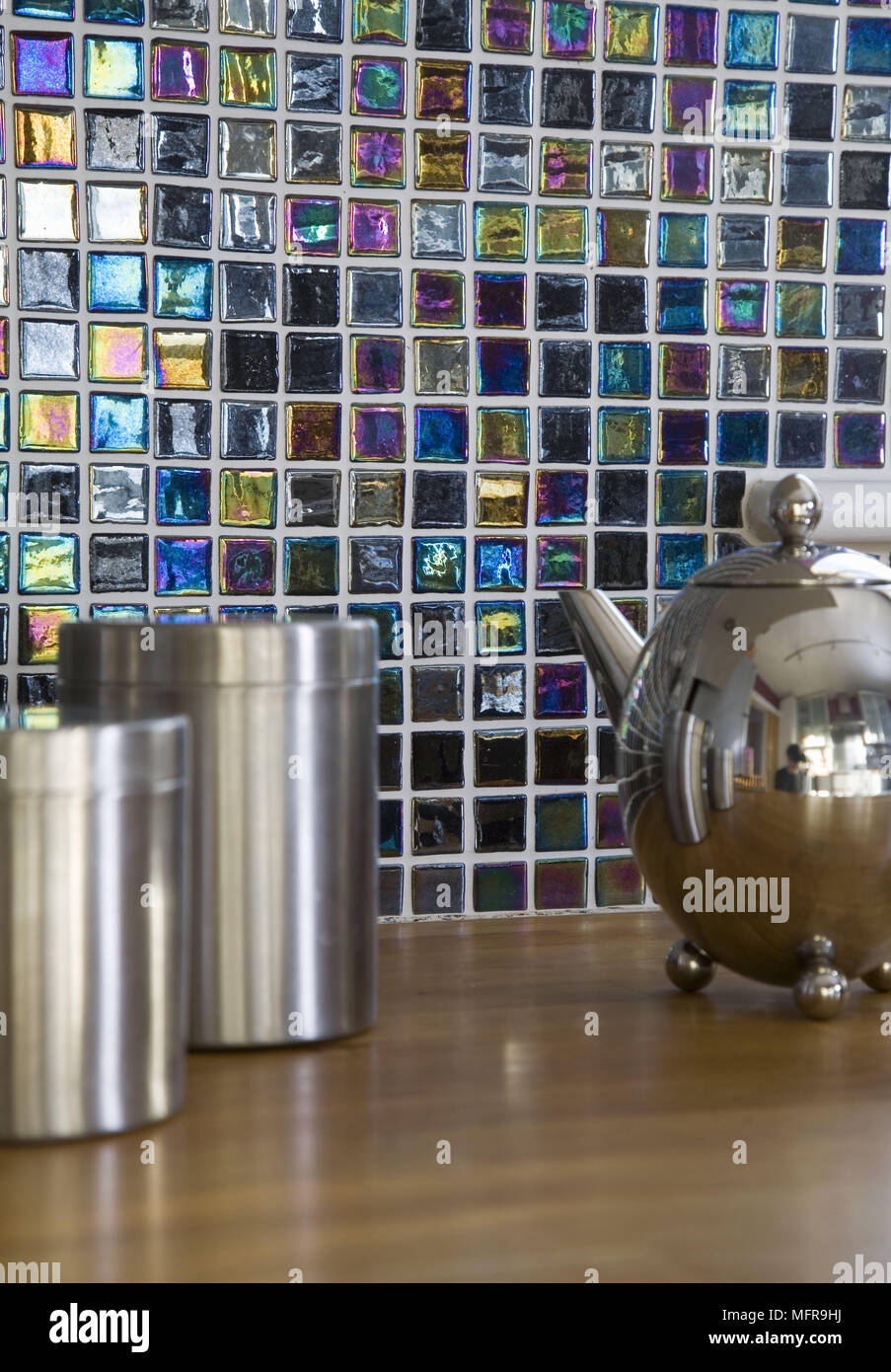Chrome storage containers and teapot on worktop with iridescent tiled wall Stock Photo Alamy