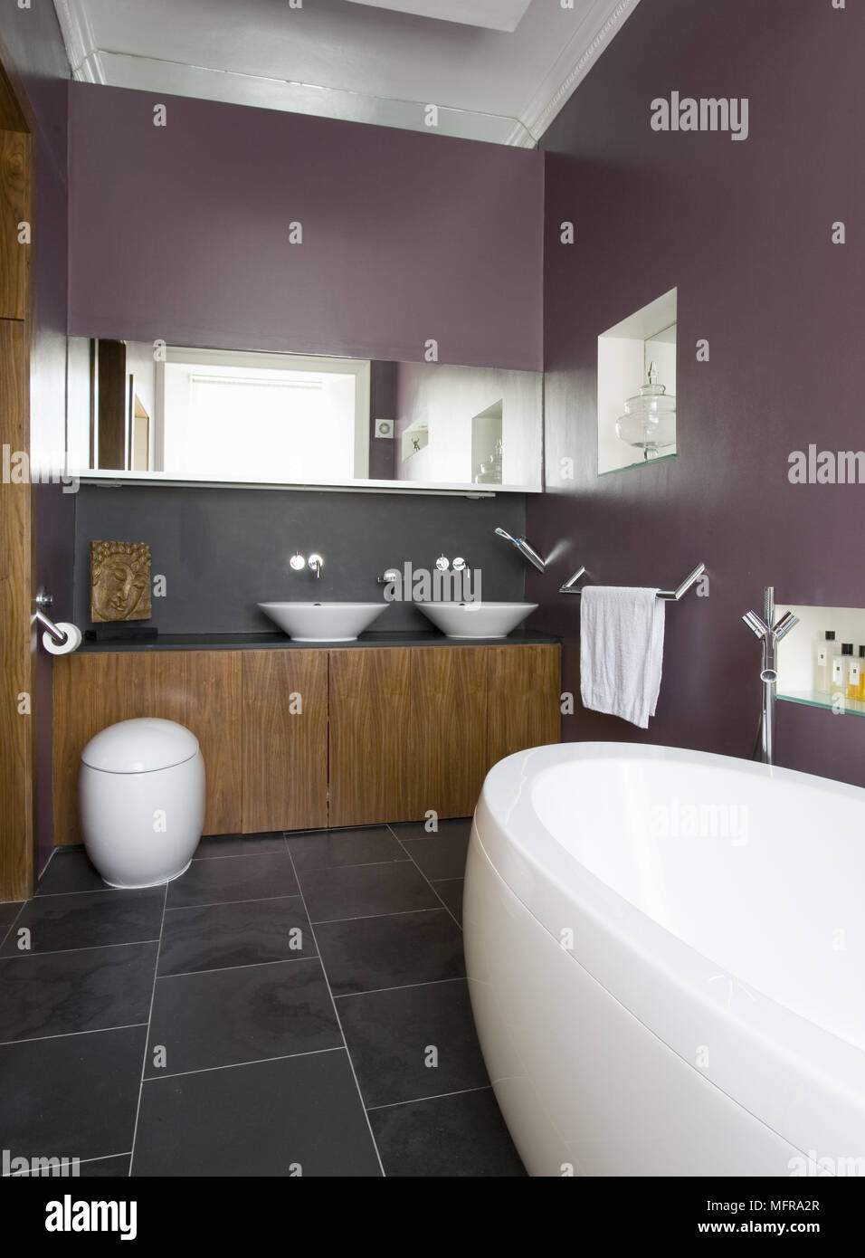 Pair of washbasins set on cupboard unit in contemporary plum colour bathroom Stock Photo