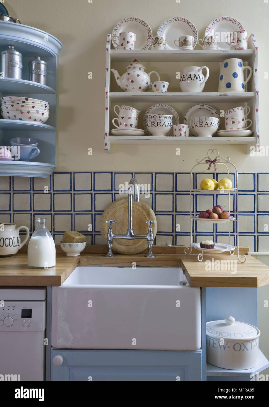 Tableware displayed on shelves above old fashioned style Belfast kitchen sink Stock Photo