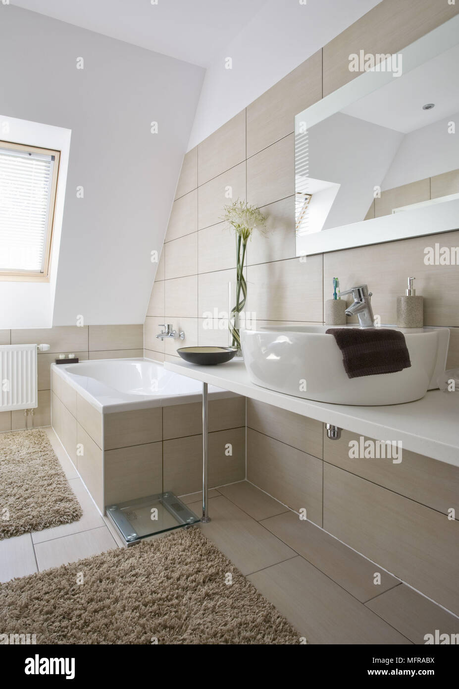 Washbasin set on shelf unit next to bathtub in neutral colour contemporary bathroom Stock Photo