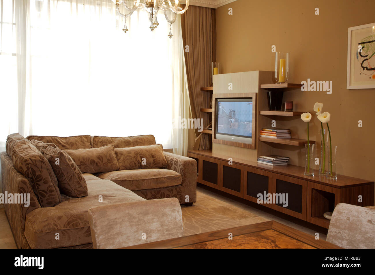 Sitting room with inbuilt flat screen television and chandelier above ...