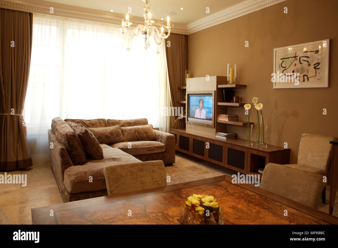Sitting room with inbuilt flat screen television and chandelier above ...