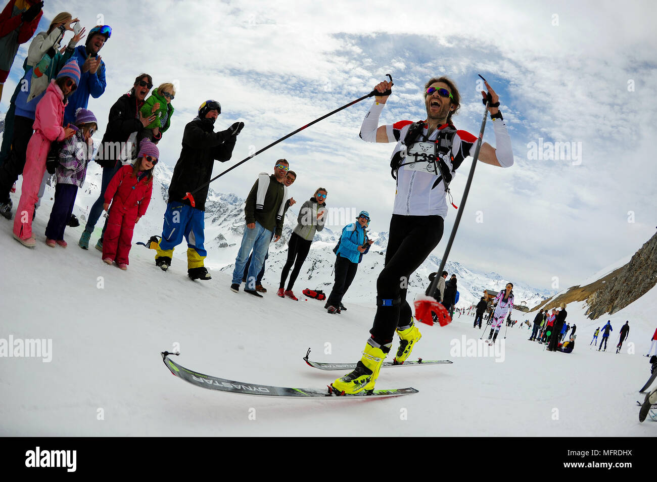A man is cheered on as he competes in the X3 triathlon which finished with ski touring in Courchevel in the French Alps Stock Photo