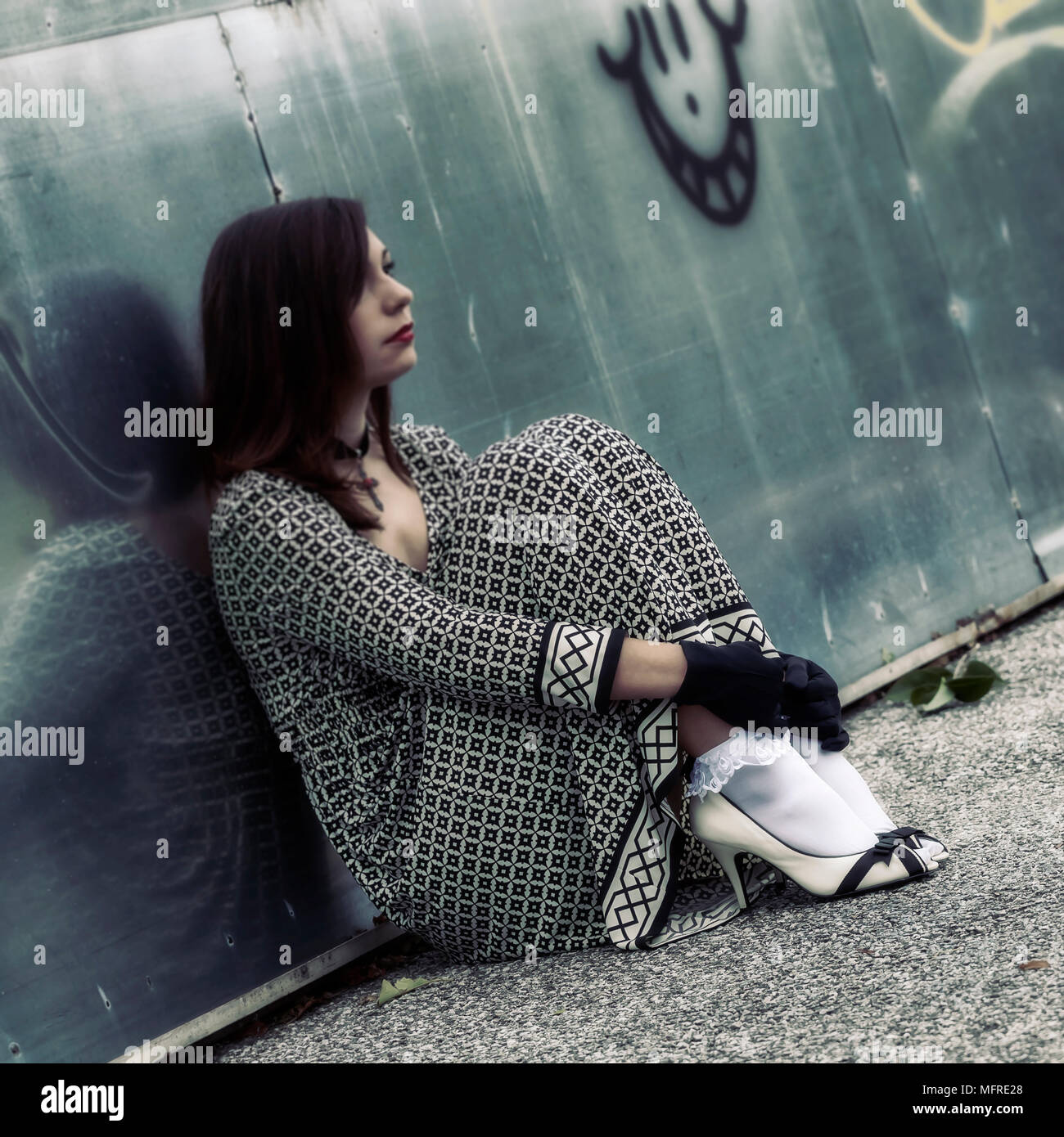 Sad girl sitting against wall hi-res stock photography and images