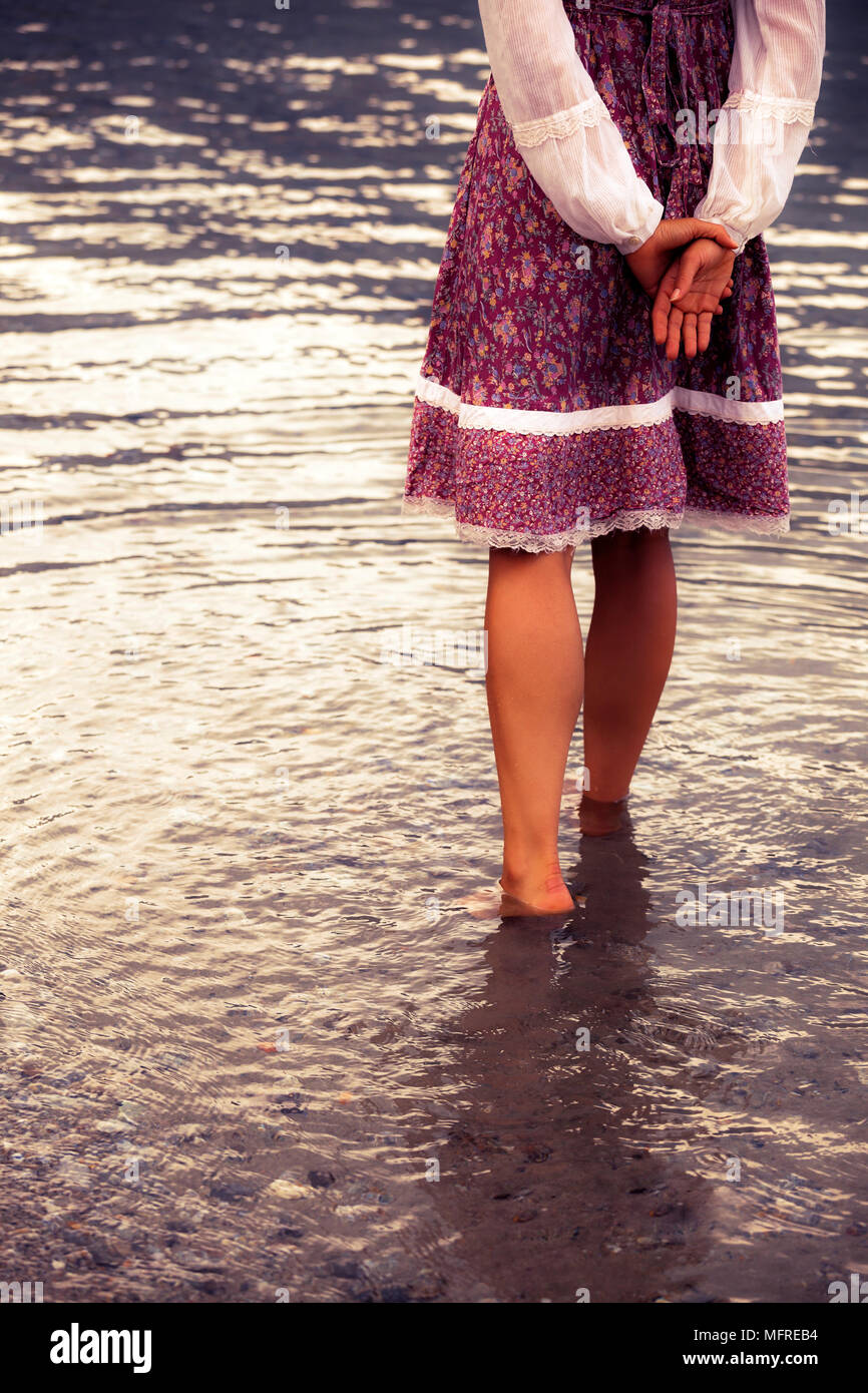 a girl in a vintage dress is standing in the water Stock Photo