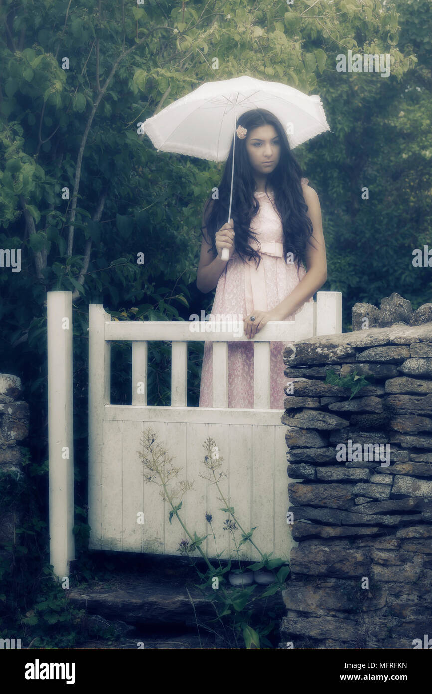 a beautiful woman with long black hair standing in a vintage pink dress ...