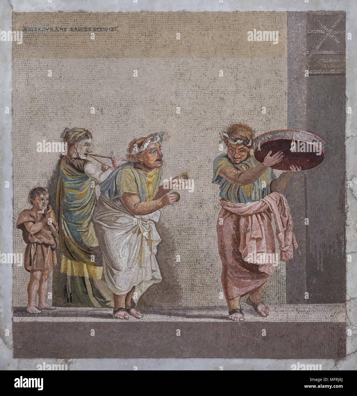 Comedy scene depicted in the Roman mosaic from Villa de Cicero (Villa of Cicero) in Pompeii, now on display in the National Archaeological Museum (Museo Archeologico Nazionale di Napoli) in Naples, Campania, Italy. Street musicians are depicted playing musical instruments often connected with the cult of Cybele: tambourine, small cymbals and double flute (tibia). The mosaic depicts an episode from a comedy, since the figures are wearing theatrical masks.  Signature on the top: signed by Dioskourides of Samos. Stock Photo