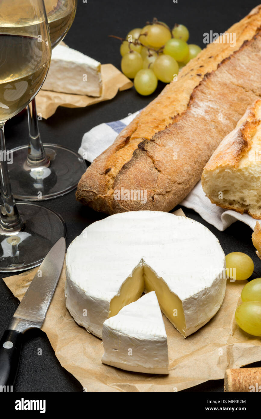 brie cheese, baguette and two glasses of white wine on dark concrete background Stock Photo Alamy
