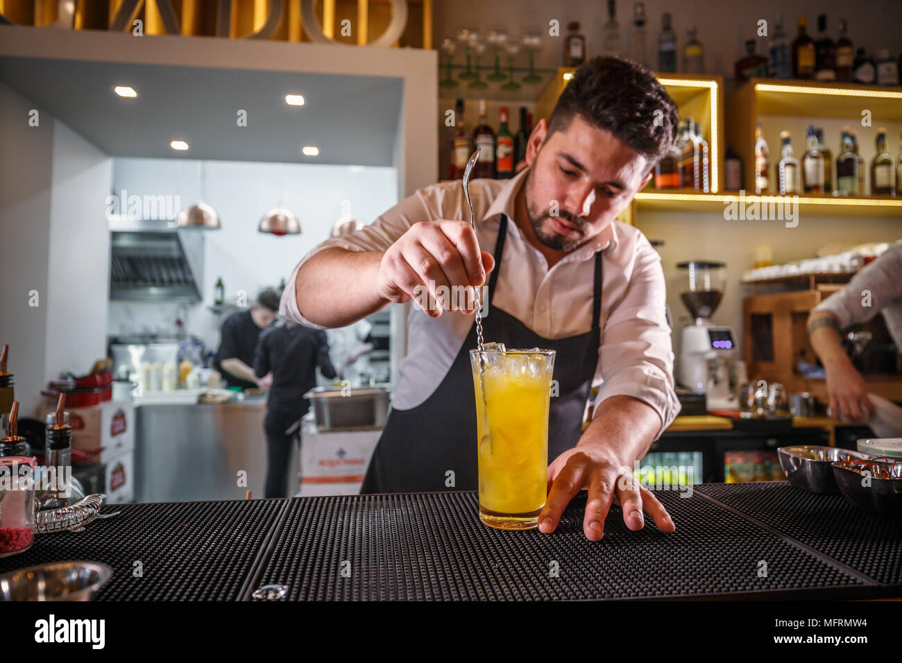 Bartender behind the bar counter stirring a non-alcoholic drink with steel swizzle spoon Stock Photo