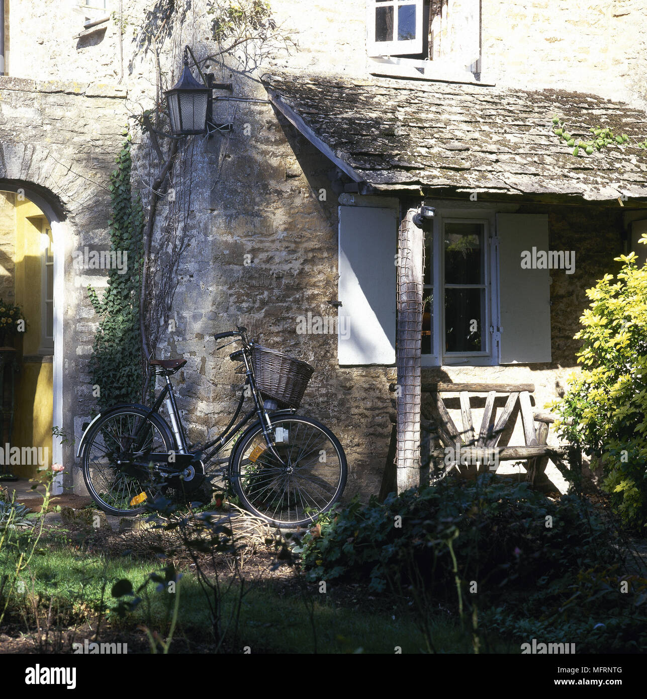 Exterior of stone cottage with covered patio area and bicycle leaning against wall, Stock Photo