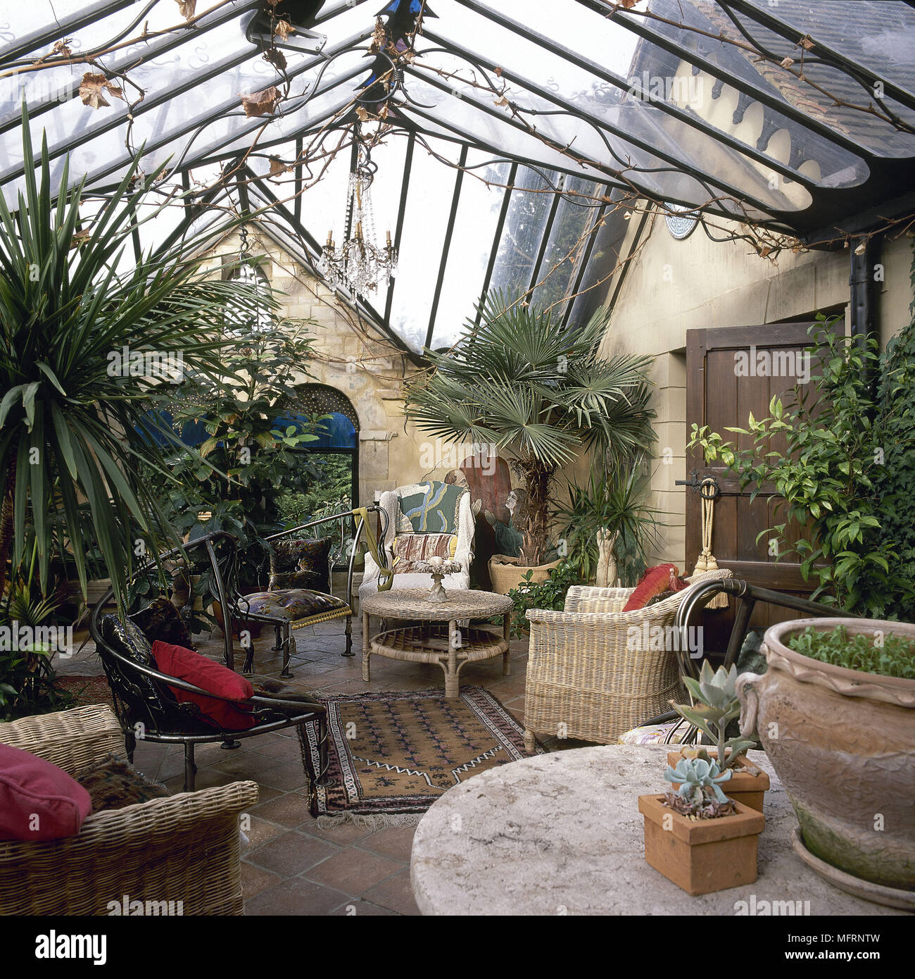 Country style conservatory, garden room with cane furniture and palm trees, Stock Photo